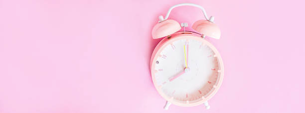 istock Background with alarm clock on pink paper background. Banner for web design. Place for text. Top view. Flat lay 1187255321