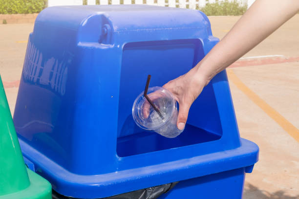 istock Close-up hand throwing empty plastic glass in the blue recycling bin. 1187255361