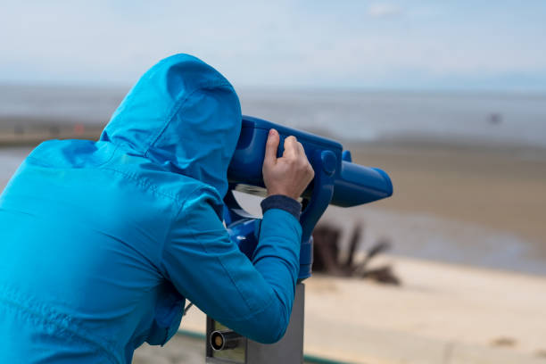 istock Man in blue coat looking on sea using coin operated binocular viewe 1187256200