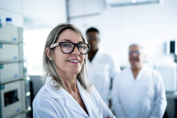 verticale de scientifique de sourire regardant l'appareil-photo - healthcare and medicine smiling group of people lab coat photos et images de collection