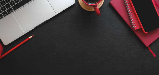 istock Top view of modern workplace with laptop computer and red office supplies on black table 1187258412