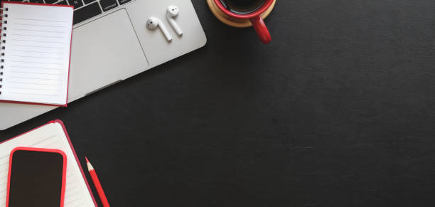 istock Top view of dark modern workplace with notebook, laptop computer and office supplies on black table 1187258431