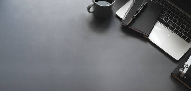 istock Overhead shot of dark stylish workspace with laptop computer black notebook on black table 1187258456
