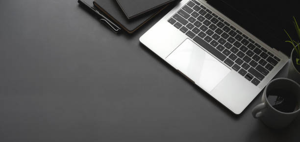 istock Overhead shot of dark stylish workspace with laptop computer black notebook on black table 1187258517