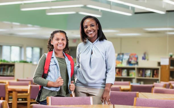 istock Mixed race girl with teacher or librarian in library 1187260241