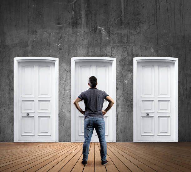 istock Young man standing looking and choosing door 1187262879