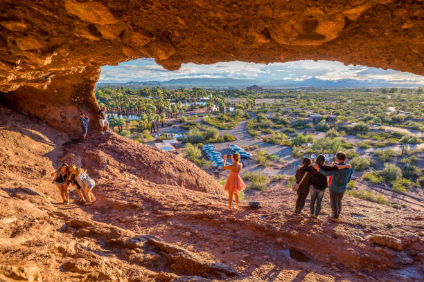Mouth of Hole-in-the-Rock People snap pictures of themselves in the mouth of Hole-in-the-Rock, a tourist attraction in Papago Park, Arizona. It was once used by the ancient Hohokam people to mark the turn of the seasons. butte rocky outcrop photos stock pictures, royalty-free photos & images