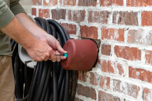 Photo of Hands installs faucet cover to protect pipes from freezing weather.