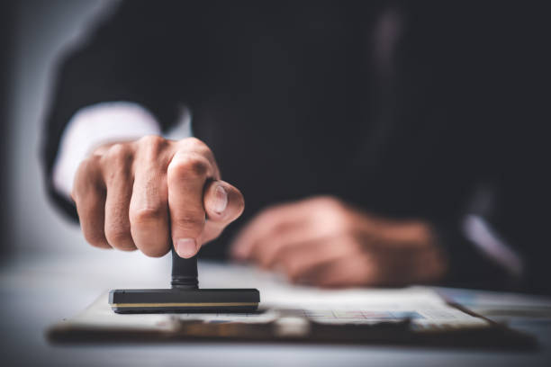 istock Close-up Of A Person's Hand Stamping With Approved Stamp On Text Approved Document At Desk,  Contract Form Paper 1187276031