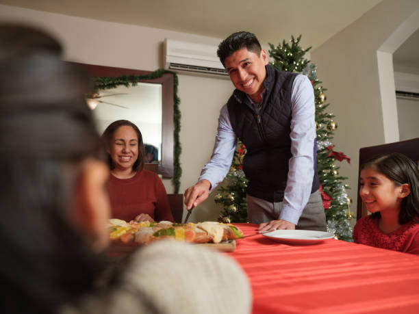 Happy family celebrating Epiphany with rosca de reyes in Mexico.