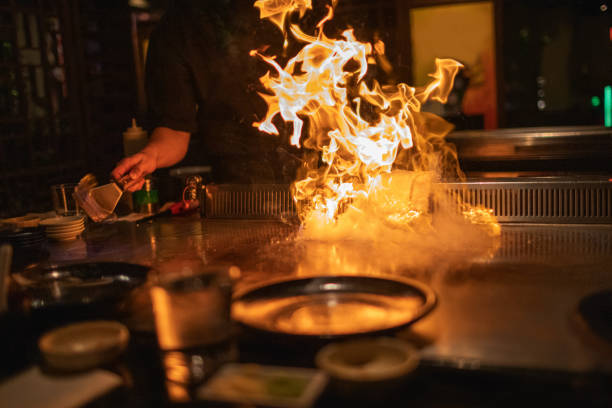 chef teppanyaki cocinando con llamas - teppan yaki fotografías e imágenes de stock