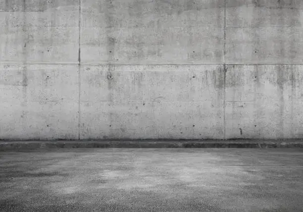 Empty parking lot, interior background with gray concrete wall and asphalt flooring, abstract photo texture