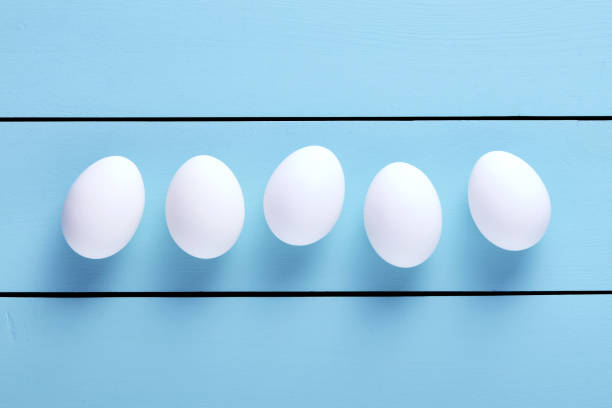 istock Fresh white farm eggs lined up in a row on blue wooden table with copy space 1187286524