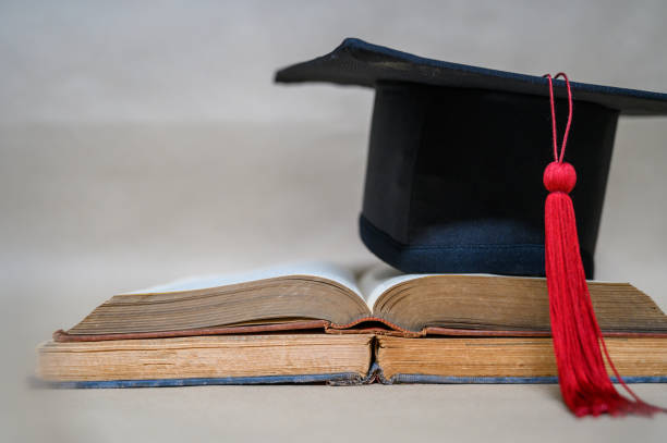 istock Black graduates' hats and books placed on brown paper 1187291216