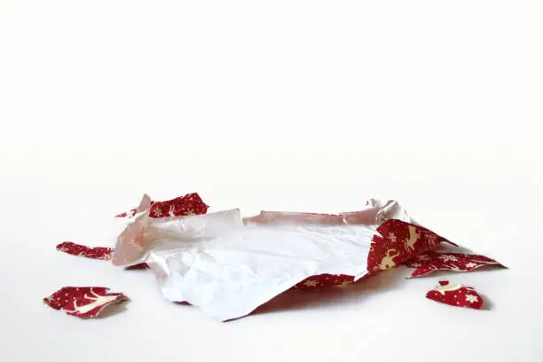 A perspective shot of a ripped piece of crumpled red Christmas or Holiday wrap, laid out on a flat surface.  A perfect template to Photoshop clearcut items onto for a festive layout.