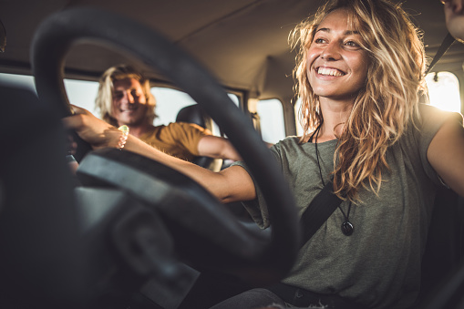 Happy woman having fun while driving her boyfriend during a road trip.