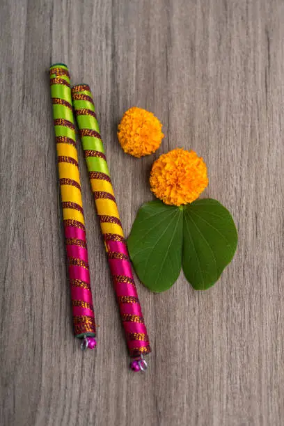 Indian Festival Dussehra and Navratri, showing golden leaf (Bauhinia racemosa) and marigold flowers with Dandiya sticks on a wooden background