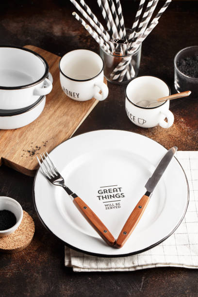 vajilla y cubertería sobre un fondo oscuro con espacio de copia. platos de metal blanco, cuencos, tazas y cubiertos con asas de madera. conjunto de platos - salt domestic kitchen bowl sparse fotografías e imágenes de stock