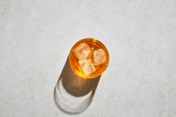 glass of elegant whiskey with ice cubes on white stone under hard hot sunlight - hard drink imagens e fotografias de stock