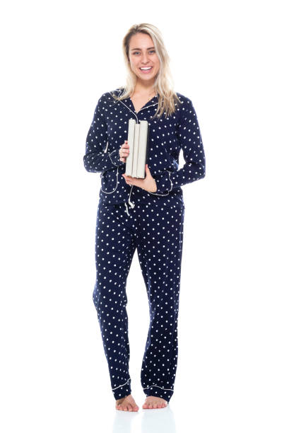 Full length / front view / one person of 20-29 years old adult beautiful blond hair / long hair caucasian female / young women student / university student standing wearing pajamas / nightwear who is smiling / happy / cheerful / laughing / learning / studying / cool attitude and holding book / textbook longitud completa / vista frontal / una persona de 20-29 años de edad adulto hermoso cabello rubio / pelo largo mujer caucásica / mujeres jóvenes estudiante / estudiante universitario de pie usando pijama / ropa de noche / actitud fresca y sosteniendo l