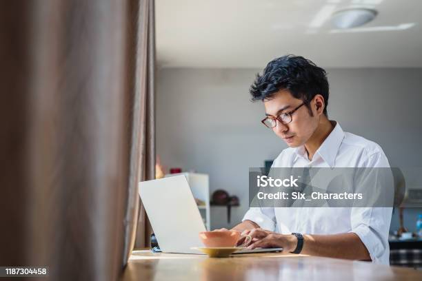 Young Asian Business Man Working With Laptop Computer While Sitting In Coffee Shop Cafe Stock Photo - Download Image Now