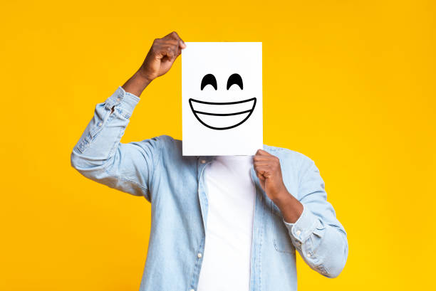 istock African man hiding face behind paper with drawn happy emoticon 1187313021