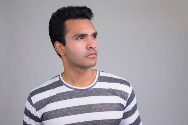 Studio shot of young handsome Indian man against white background