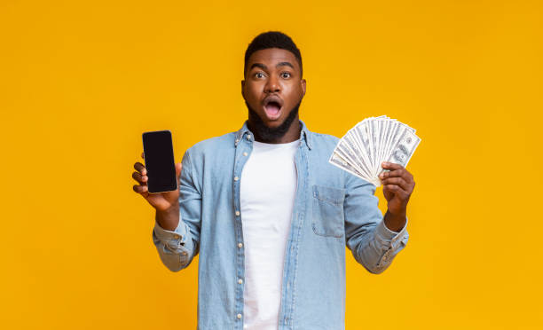istock Afro guy holding cellphone with black screen and dollar cash 1187320154
