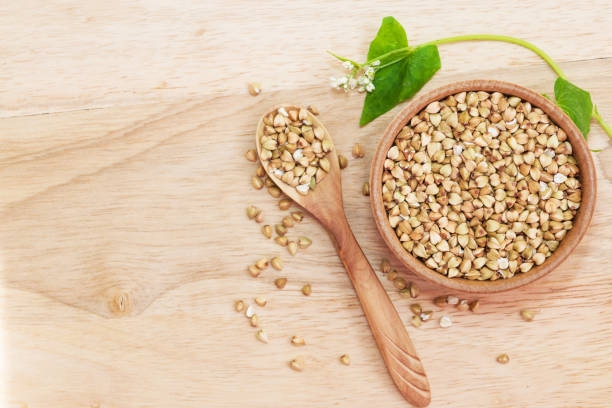 istock Raw green unprocessed buckwheat on a wooden table in a plate, top view. Copy space, space for text, flat lay 1187321313