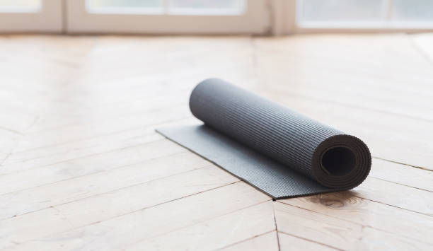 istock Rolled up yoga mat on wooden floor 1187321323