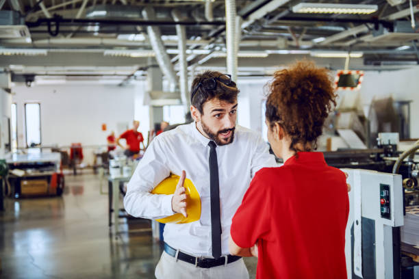 angry caucasian bearded director in shirt and tie arguing with his sloppy female employee. printing shop interior. - foreman imagens e fotografias de stock