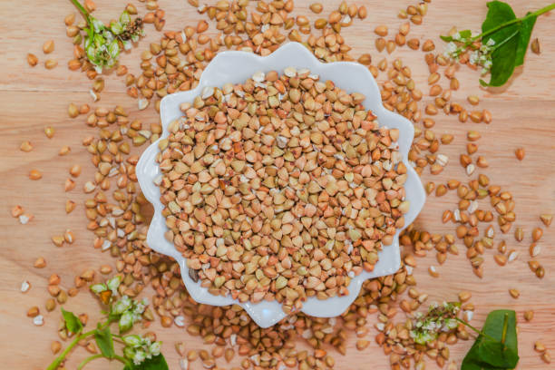 istock Raw green unprocessed buckwheat on a wooden table in a plate, top view. Copy space, space for text, flat lay 1187321931