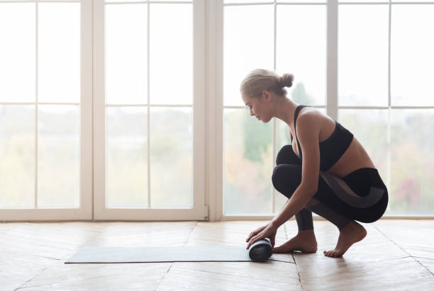 istock Woman after practicing yoga, rolling yoga mat at studio 1187322021