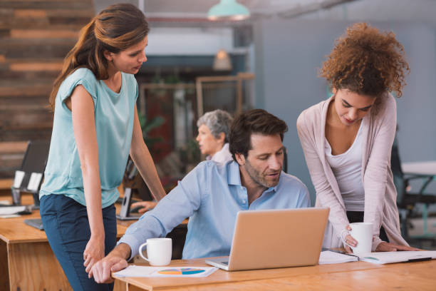 istock Three office coworkers using a laptop and discussing paperwork 1187322338