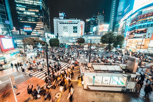 Tokyo, Japan - Nov 3, 2019: Crowded people walking, car traffic on Shibuya scramble crossing at night. Tokyo landmark tourist attraction, Japan tourism, Asia transportation or Asian city life concept