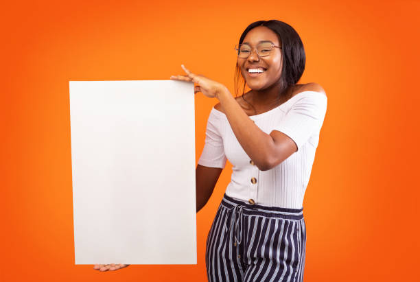 chica afroamericana sosteniendo placa en blanco de pie en el estudio, mockup - 20s attractive female beautiful people blackboard fotografías e imágenes de stock