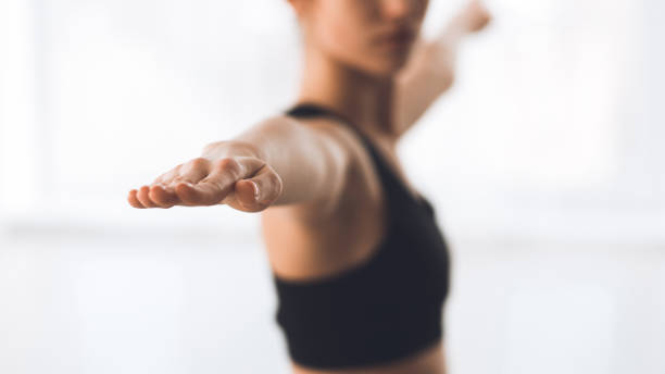 Woman exercising yoga in warrior pose, focus on hand Woman exercising yoga in warrior pose, focus on hand. Girl practicing yoga in studio, panorama warrior position stock pictures, royalty-free photos & images