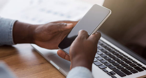 istock Black male hands using smartphone with blank screen and laptop 1187322609