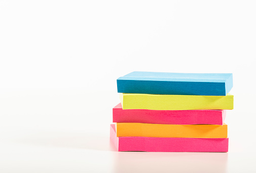 A stack of four sticky note pads in different colours.