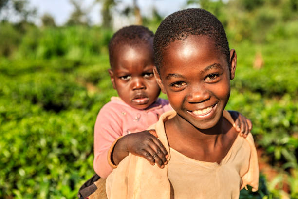 彼女の赤ちゃんの弟、ケニア、東アフリカを抱いている小さなアフリカの女の子 - africa child village smiling ストックフォトと画像