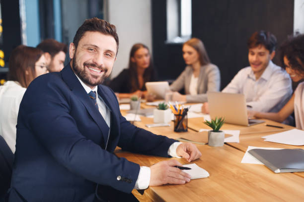 istock Happy businessman smiling to camera with colleagues on background 1187328186
