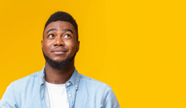 istock Cynical guy looking upwards at copy space on yellow background 1187328696