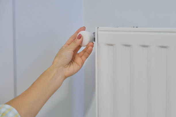 istock Hand on heating radiator regulates the temperature with thermostat regulator 1187329676