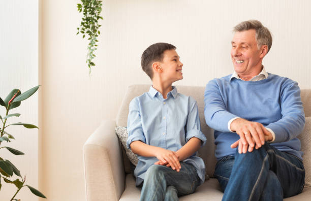 istock Happy Boy And Grandfather Sitting On Sofa At Home 1187330044