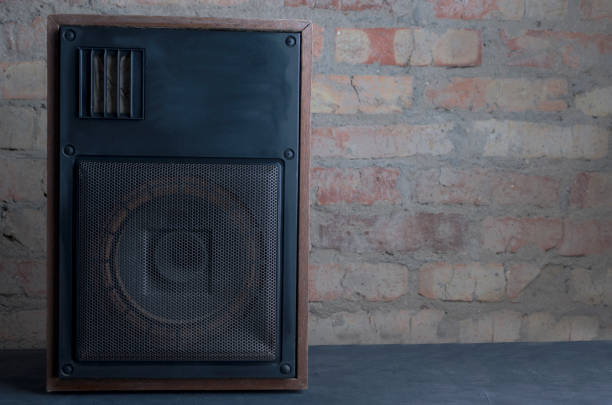 Bookshelf speaker standing on the dark shelf against brick wall.Empty space for text Black powerful speaker standing on the floor against vintage brick wall.Concept of recording or music studio home recording studio setup stock pictures, royalty-free photos & images