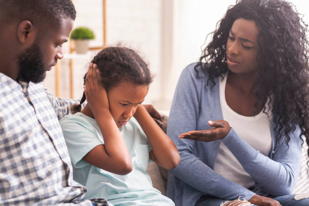 Little girl closing her ears not to listen parents scolding Family education. Little black girl closing her ears not to listen parents scolding man closing ears photos stock pictures, royalty-free photos & images