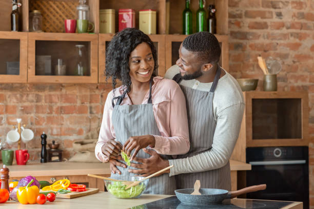 istock Man hugging his wife from behind while cooking 1187331336