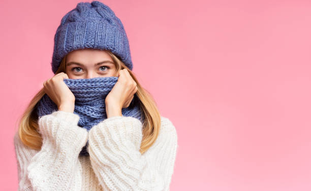 istock Enigmatic winter girl hiding from cold over pink background 1187331559