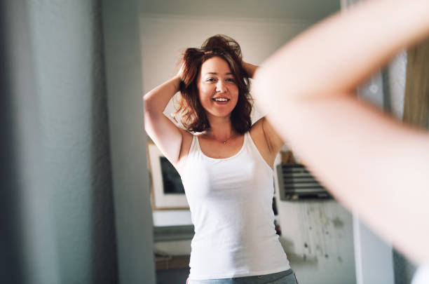 Cropped shot of an attractive young woman admiring her hair while standing in front of the mirror in her bedroom at home