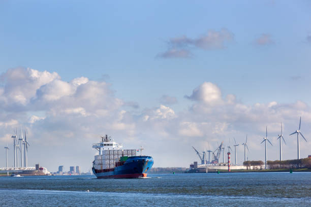 Container ship on canal Hartelkanaal in Rotterdam in the Netherlands with the Maeslantkering near the turbines in the background